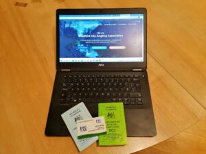 new website on laptop with membership books and card