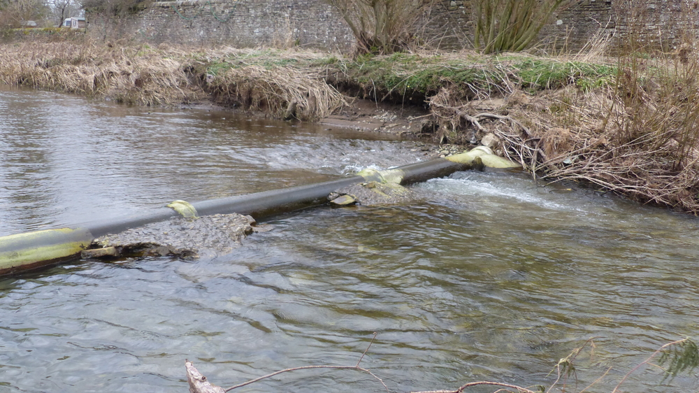 Undermined sewage pipe in river